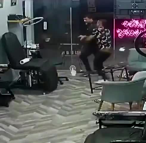 Guy charges a man with a shotgun in a tattoo parlor