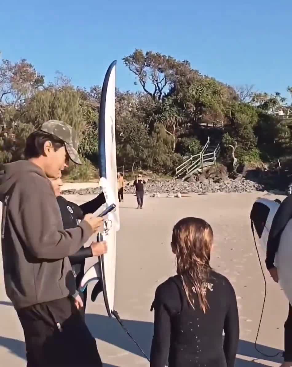 Local father Brad Ross holds the remains of his surfboard after a shark took a clean bite out of it at Cabarita Beach