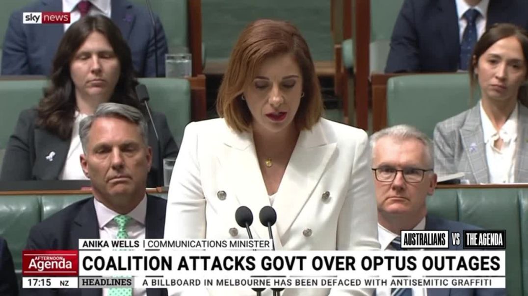 Communications Minister Anika Wells has defended flying to New York to promote the social media ban at the United Nations while Australians were dying during the Triple-Zero outage, blaming Optus inst